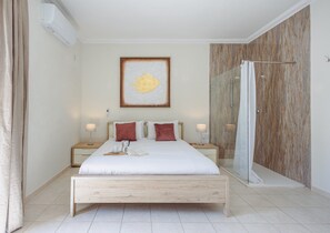 A modern bedroom with a wooden bed, a glass shower enclosure, and a wall-mounted artwork. - Spacious 2BR Sliema Apartment (Sliema)