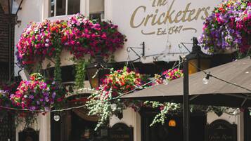 En pub med udeservering, et skilt med 'The Cricketers' og blomsterkasser hængende ned.