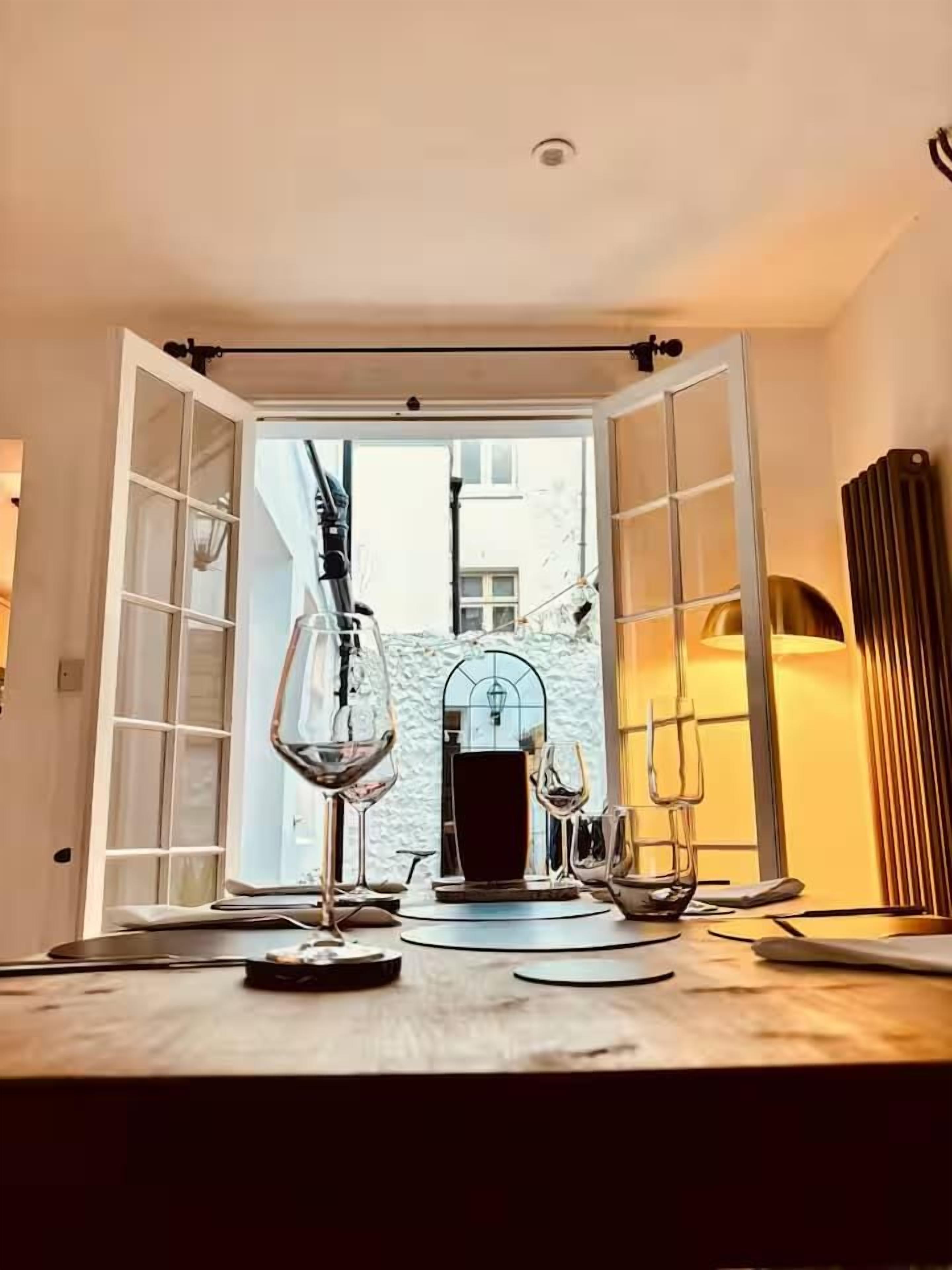 Uma sala de jantar com uma mesa posta para dois, uma taça de vinho e um castiçal.