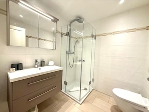 A modern bathroom with a glass-enclosed shower, a white sink with a mirror above, and a toilet. - Halligblick Apt. 11 (Wyk auf Foehr)