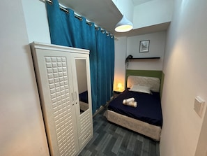 A bedroom with a bed, a wardrobe, a nightstand with a lamp, and a framed picture on the wall. - Double Bed partition Room in Tecom (Dubai)