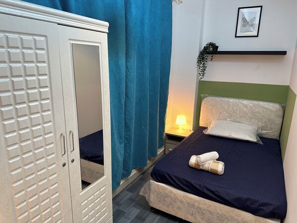A bedroom with a bed, a nightstand, a lamp, a wardrobe, and a framed butterfly picture on the wall. - Double Bed partition Room in Tecom (Dubai)