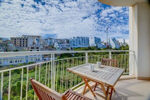 A balcony with a table and chairs, overlooking a cityscape with buildings and greenery. - Modern Apartment Steps From Balluta Bay (St. Julian's)