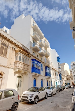 A row of white buildings with blue balconies and a clear blue sky. - Trendy 3BR Home by the Waterfront (Gzira)