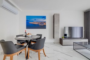 A modern dining area with a round table, black chairs, and a cityscape painting on the wall. - Trendy 3BR Home by the Waterfront (Gzira)