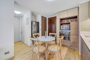 Un ambiente compatto con angolo ristoro, angolo cottura e una porta in legno che dà su un'altra stanza.