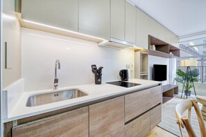 A modern kitchen with a built-in stove, a sink, and a countertop with a coffee maker. - Ñuñoa Botanic 2D - Estacionamiento y AC (Ñuñoa)