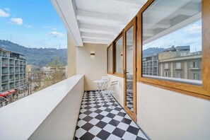 Uma varanda com piso xadrez, uma mesa pequena e cadeiras.