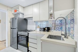 Uma cozinha moderna com eletrodomésticos de aço inoxidável, painel de azulejos e uma pia embutida.