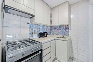 Une cuisine de taille réduite, équipée d’une cuisinière à gaz, d’un grille-pain et d’un évier.