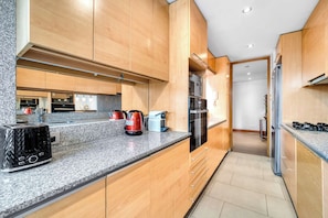 Een moderne keuken met houten kastjes, granieten aanrechtbladen en roestvrijstalen apparatuur.