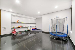 Een schone, moderne kamer met een trampoline, speelgoed en een speelruimte.