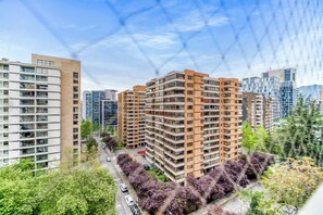Een hoog appartementencomplex met meerdere balkons, omringd door andere gebouwen en bomen.
