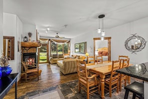 A spacious living area with a fireplace, wooden furniture, and large windows offering a view of the outdoors. - Near the Ski Area | Cozy Fireplace & Ski Shuttle (Steamboat Springs)