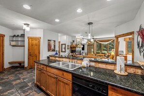 A spacious kitchen with a large island, wooden cabinets, and a dishwasher. - Near the Ski Area | Cozy Fireplace & Ski Shuttle (Steamboat Springs)