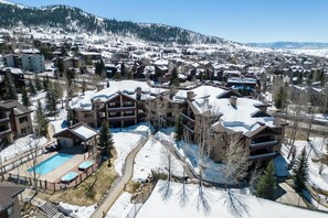 Um resort com vários edifícios, piscina e paisagem coberta de neve.