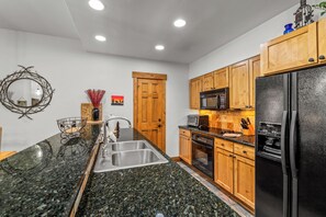 A modern kitchen with granite countertops, stainless steel appliances, and wooden cabinets. - Near the Ski Area | Cozy Fireplace & Ski Shuttle (Steamboat Springs)