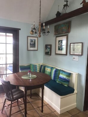 A dining area with a wooden table, chairs, and a bench with colorful cushions. - Serene 3-bedroom house near Beaches in Warwick Parish (Warwick Parish)