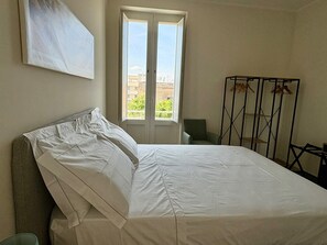 Een slaapkamer met een bed, een raam en een droogrek.