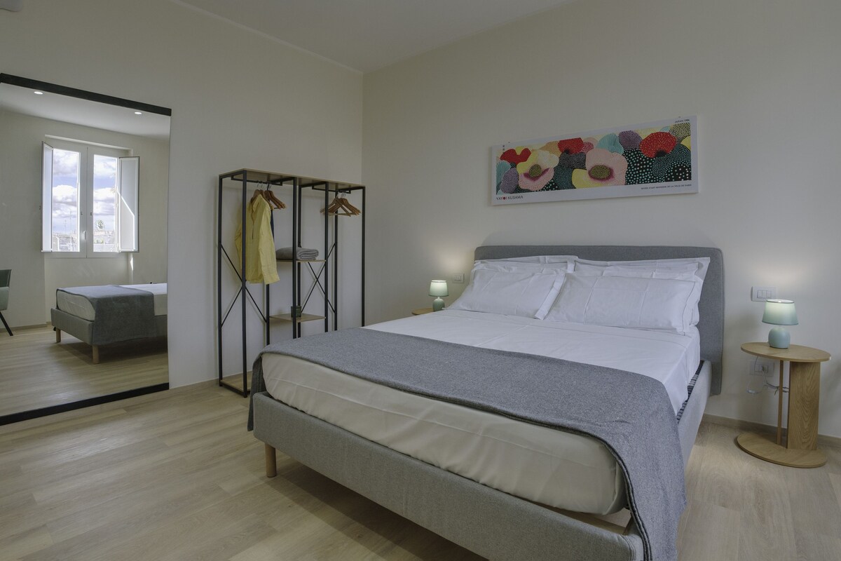A modern bedroom with a bed, bedside tables, a wardrobe, and a painting.