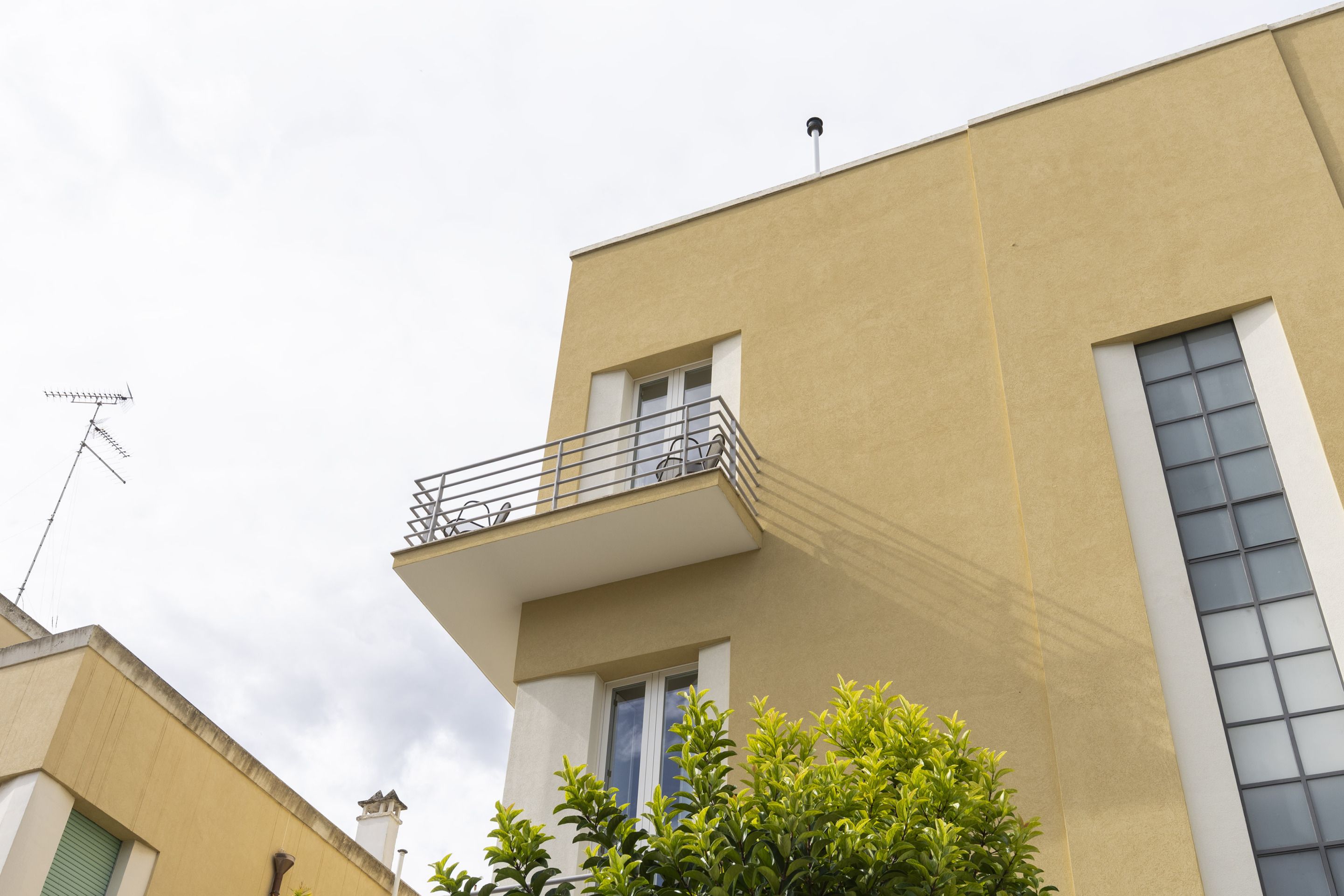 A building with a balcony, a window, and a chimney.