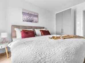 A bedroom with a large bed, a nightstand, a lamp, a wardrobe, and a wall-mounted artwork. - Apartment in Olpenitz With Swimming Pool (Kappeln)