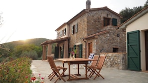 A stone building with a patio, wooden furniture, and a green door. - Natural Stone House with a Pool and Ocean View in the Maremma (Prata)