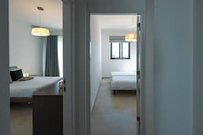 A hotel room with a bed, bedside table, lamp, and a window. - Bright and Modern 2BR Penthouse, St Julian's (St. Julian's)