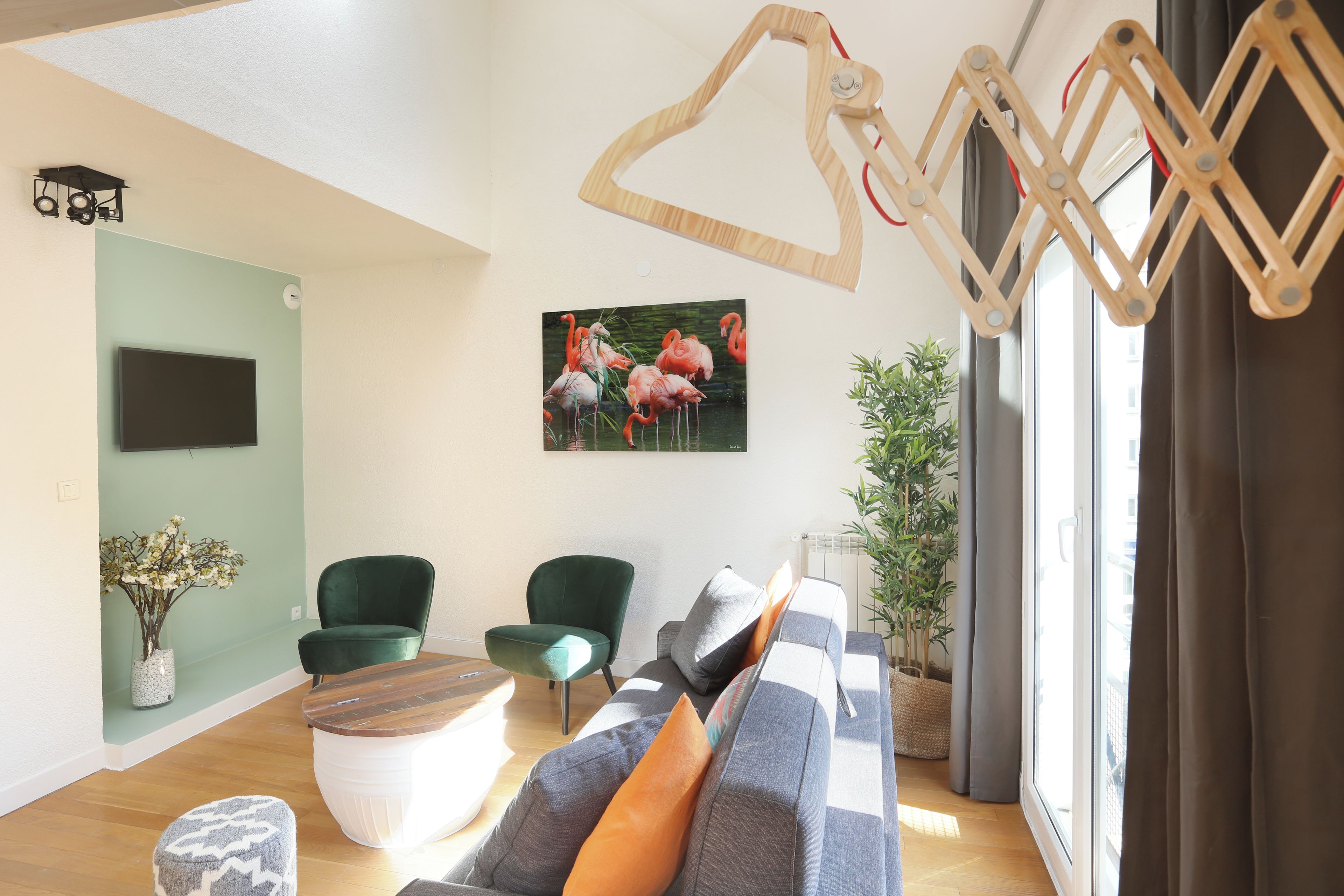 Una sala de estar moderna con un sofá, dos sillones, una mesa de centro de madera y un cuadro de flamencos.