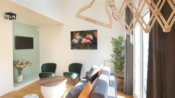 Una sala de estar moderna con un sofá, dos sillones, una mesa de centro de madera y un cuadro de flamencos.