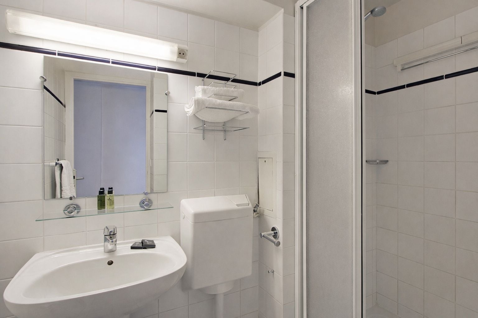Een moderne badkamer met een glazen wastafel, een toilet, een douche en een spiegel.