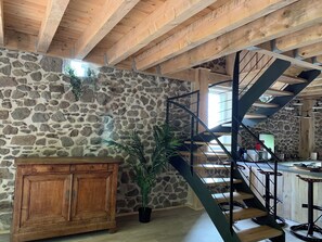 A rustic interior with a stone wall, wooden staircase, and a wooden cabinet. - La Grange de la Gratade: A Vacation Home for Recharging and Exploring (Rochefort-Montagne)