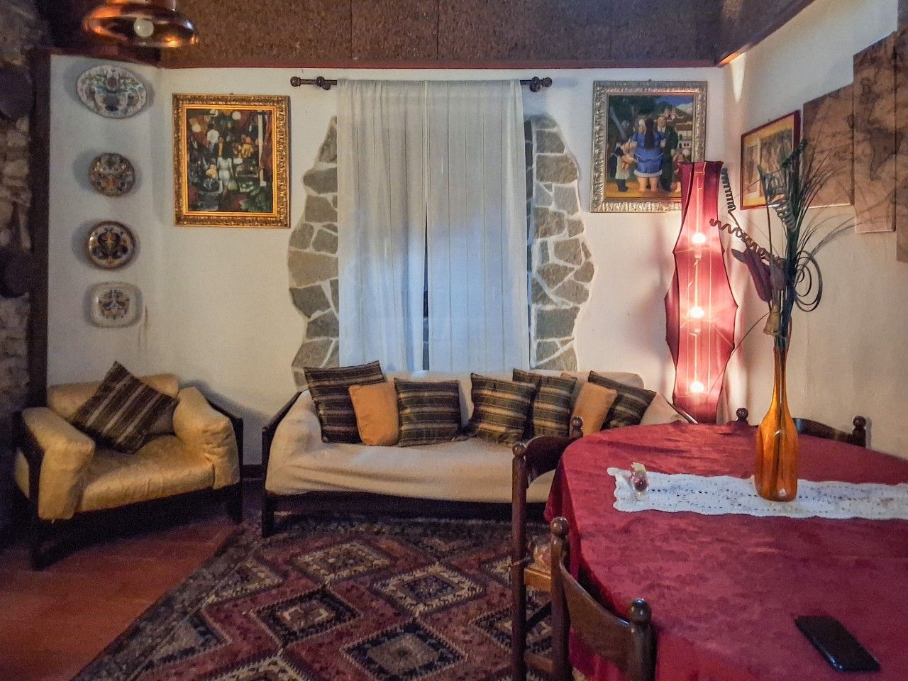 Ein gemütliches Wohnzimmer mit einer Couch, Sesseln, einem Esstisch und einer dekorativen Vase.