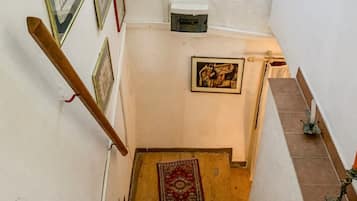A staircase with a marble top and wooden steps, leading to a landing with framed pictures and a rug.