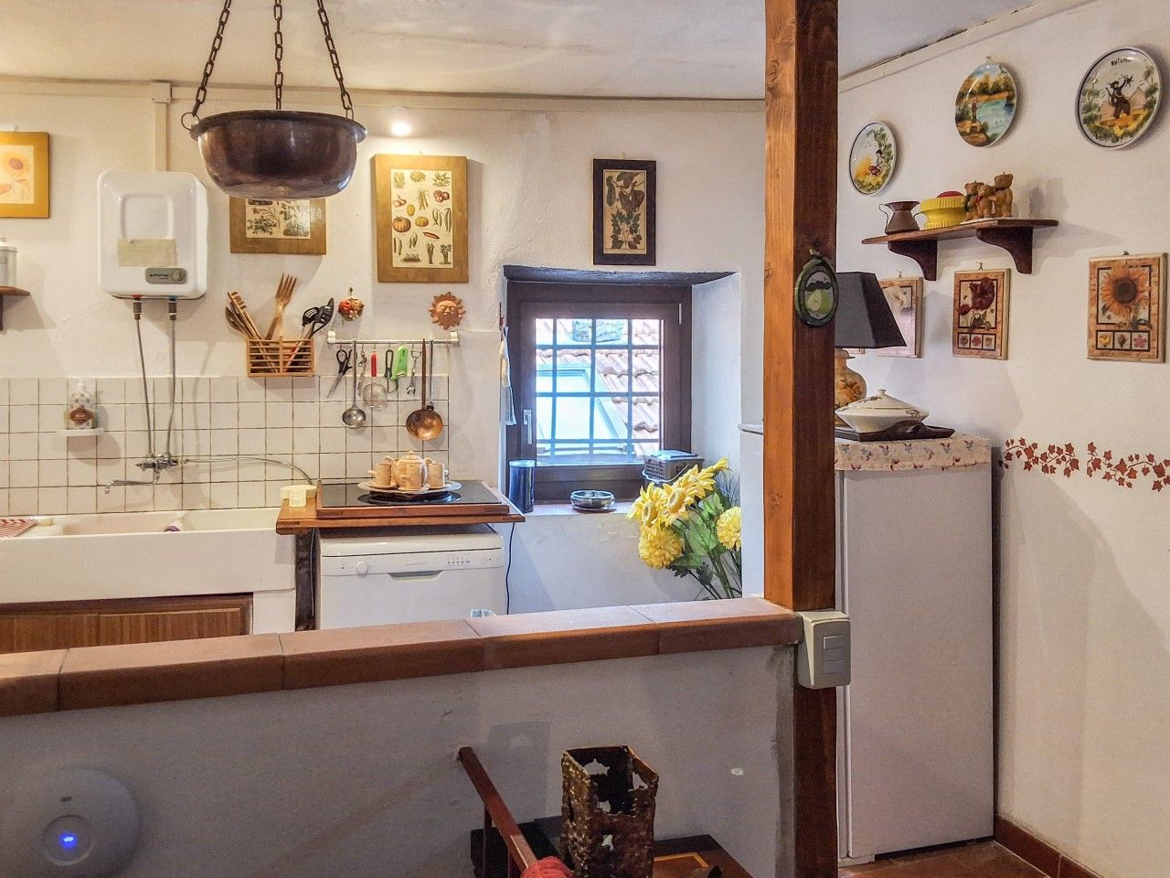 A kitchen with a window, a hanging pot rack, and various kitchen utensils.