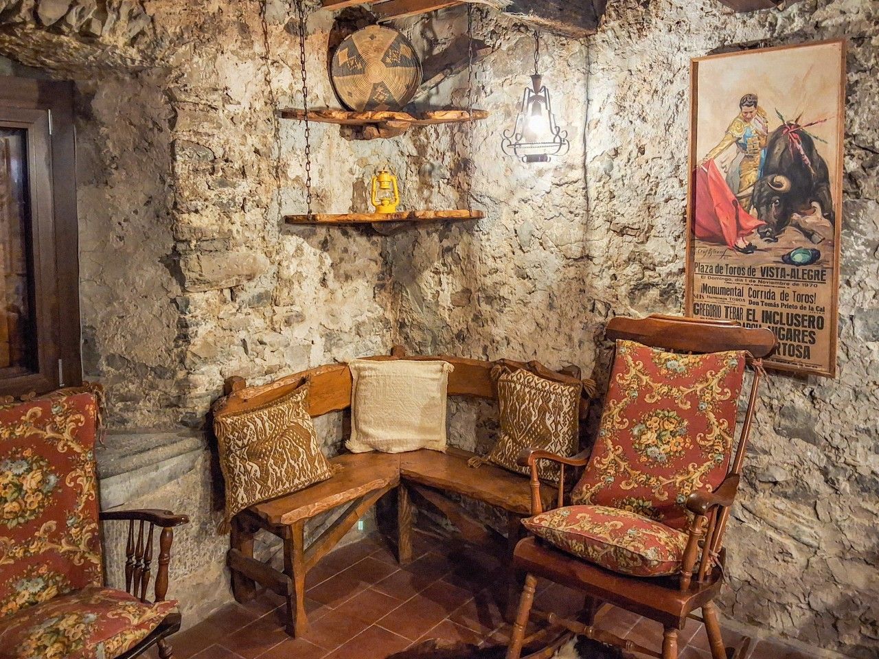 Ein rustikaler Innenraum mit Steinwänden, Holzmöbeln und einem alten Plakat.
