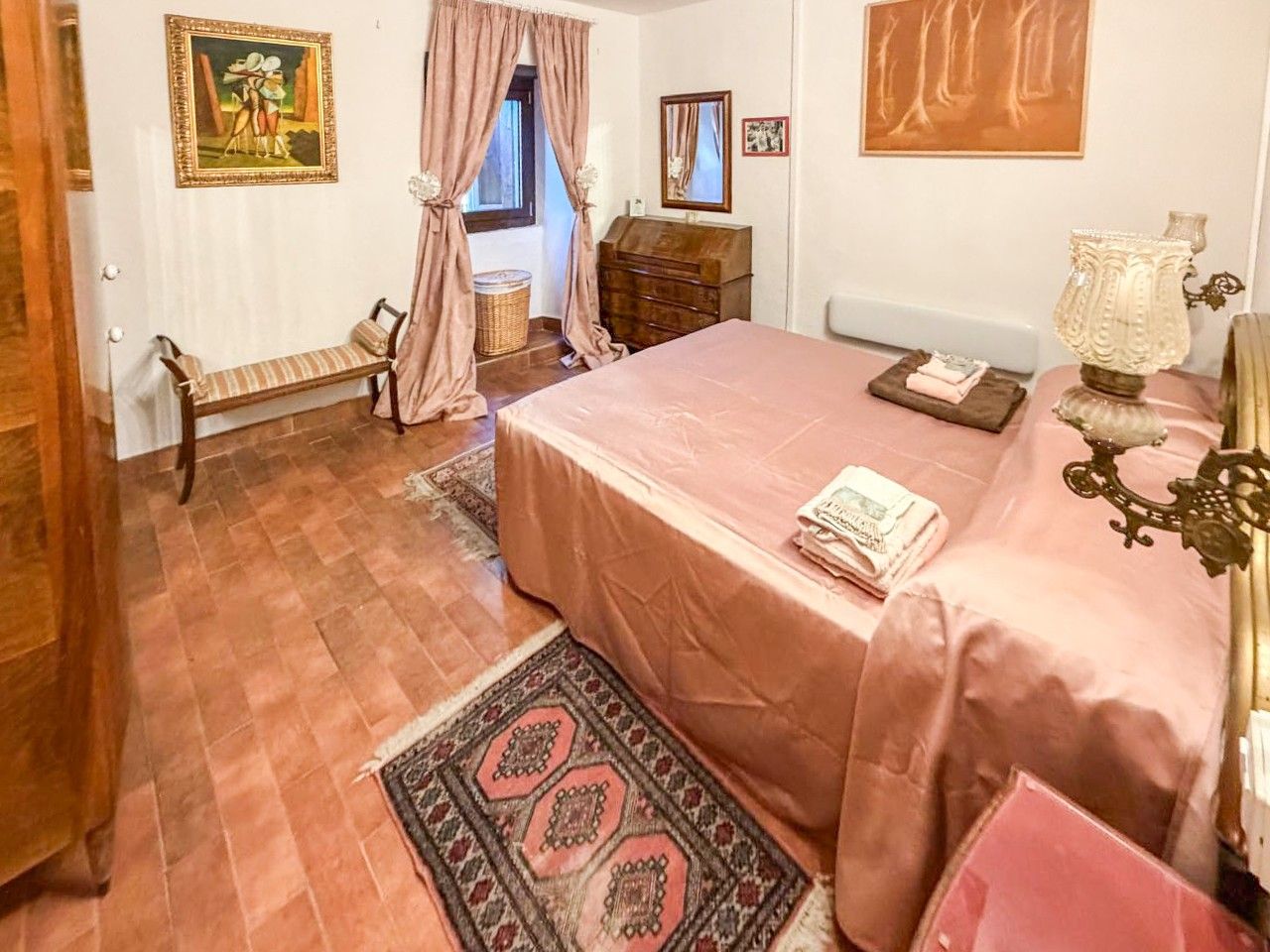 A bedroom with a bed, a bench, a dresser, a lamp, and a rug.