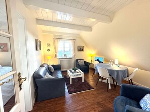 A cozy living room with a sofa, a coffee table, and a dining area with a table and chairs. - Deichhof Apt. 22 (Dunsum)