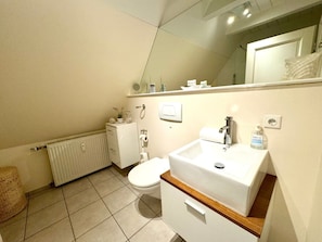 Un baño con inodoro, lavabo, espejo y radiador.