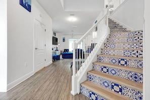 A staircase with blue and white patterned tiles, a wooden floor, and white railings. - Magical Moments at Reunion Village Retreat (Kissimmee)