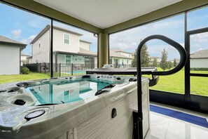 A hot tub with a view of a residential area through large windows. - Magical Moments at Reunion Village Retreat (Kissimmee)