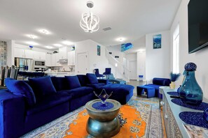 A modern living room with a blue sofa, a coffee table, and a decorative vase. - Magical Moments at Reunion Village Retreat (Kissimmee)