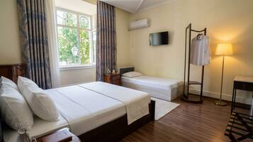 Ein Hotelzimmer mit Bett, Nachttisch, Lampe und Fernseher an der Wand.