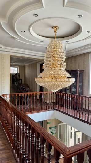Una imponente escalera de madera con barandilla y un gran candelabro ornamentado.