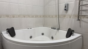 A white bathtub with two black seats, a showerhead, and a towel rack. - ARYANA KABUL HOTEL (Tashkent)