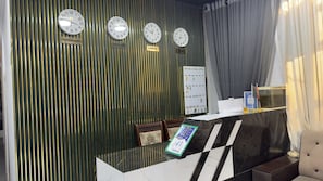 A reception desk with clocks displaying different time zones, a directory, and a sign for the Aryana Kabul Hotel. - ARYANA KABUL HOTEL (Tashkent)