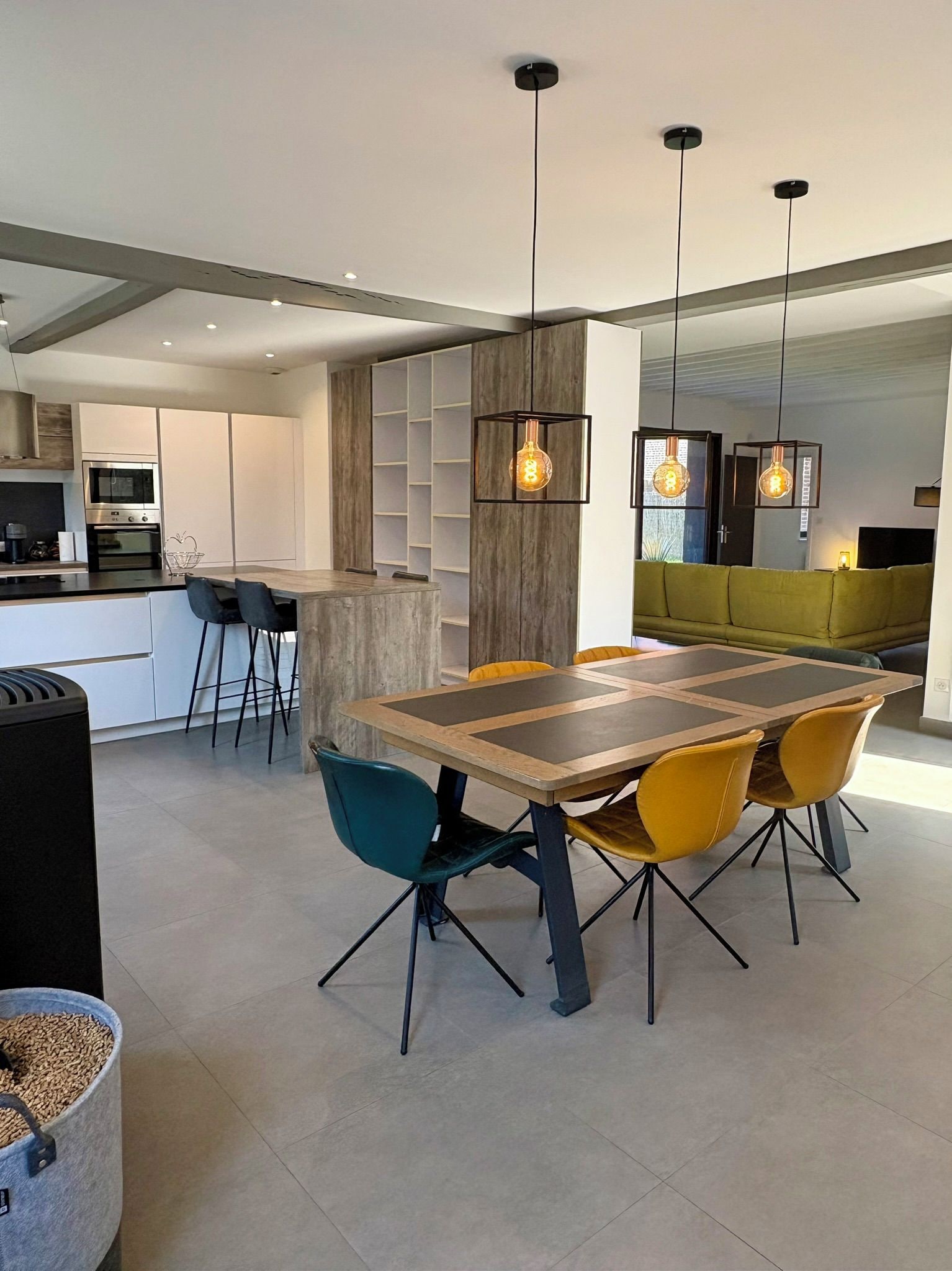 Une cuisine moderne dotée d’un îlot central, de tabourets de bar et de luminaires suspendus.