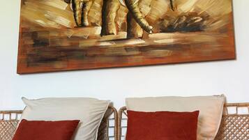 Un lit avec deux oreillers, une tête de lit et un tableau représentant des éléphants accroché au mur.