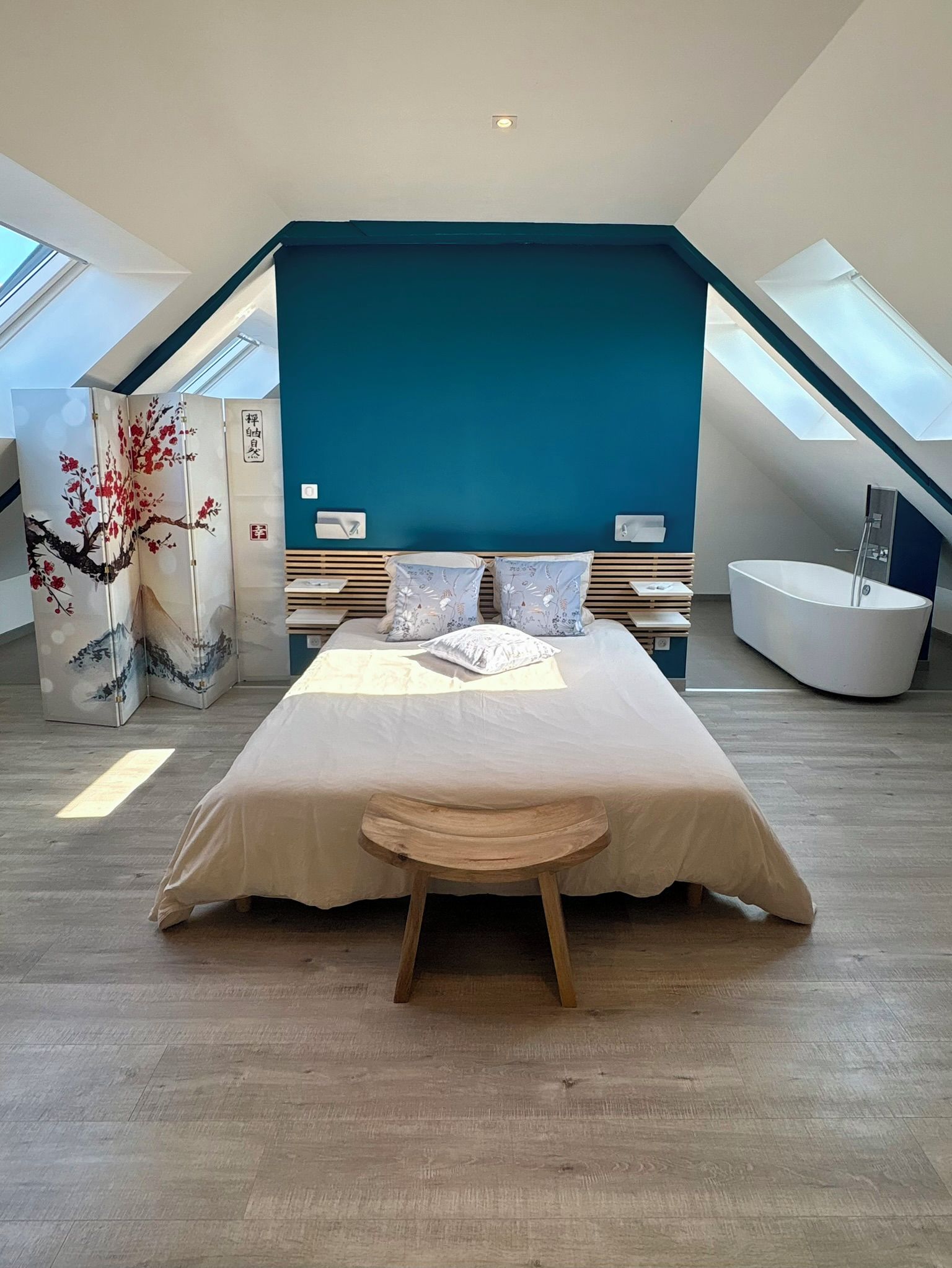 Une chambre moderne avec un grand lit, une fenêtre de toit et une baignoire.