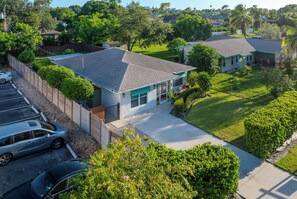 A residential house with a sloped roof, a front yard, and a driveway. - Beautiful Remodeled 3 Bedroom Pool House (Naples)